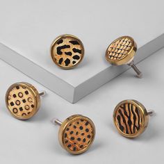 four pairs of gold and black cufflinks with animal print designs on the backs