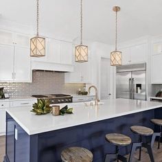 a kitchen island with stools and lights hanging from it's ceiling over the counter