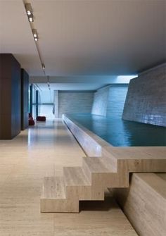 an empty room with stairs leading up to the water in the pool and light fixtures on the walls