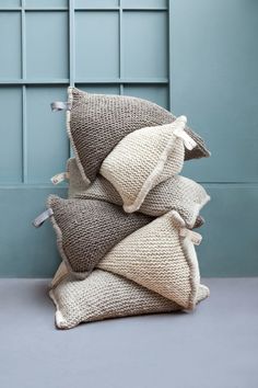 three pillows stacked on top of each other in front of a blue paneled wall