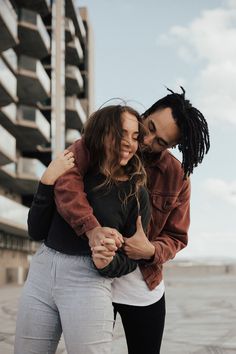 a man and woman hugging each other in front of a building