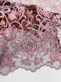 the pink lace is laying on top of the white table cloth with an intricate design