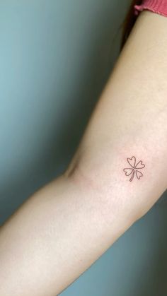 a woman's arm with a small four leaf clover tattoo on her left arm