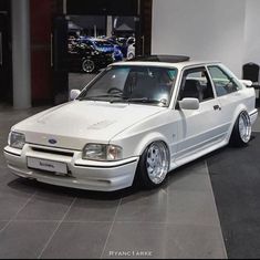 a white car is parked in a showroom