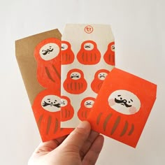 someone is holding up two cards with different designs on them, one in orange and the other in white