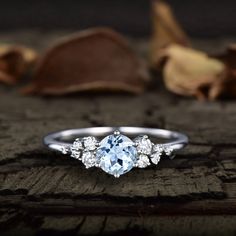 an engagement ring with a blue topaz surrounded by leaves