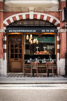 an outside view of a restaurant with tables and chairs in front of the entrance to it