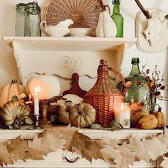 a mantle with candles, pumpkins and other decorative items on it's shelf