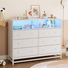 a baby's room with a dresser and toy cars on the top shelf in front of it