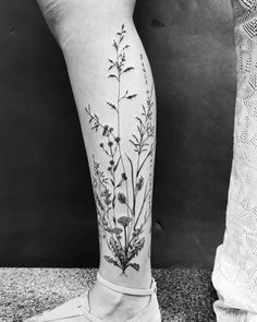 a black and white photo of two legs with flowers on them