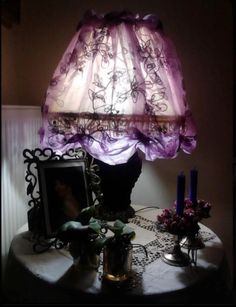 a lamp that is on top of a table next to a vase and flowers in front of it