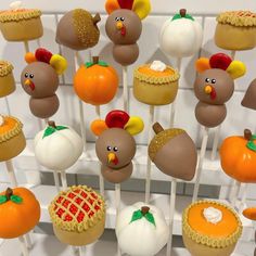 there are many cupcakes decorated like turkeys and pumpkins on the sticks