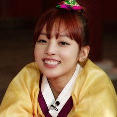 a young woman with red hair wearing a yellow kimono and smiling at the camera