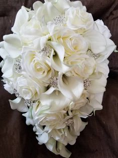 a bridal bouquet with white roses and diaper on the bottom is sitting on a brown cloth