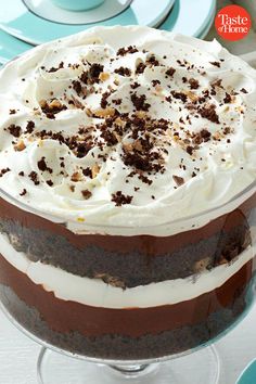 a cake with white frosting and chocolate shavings on top sitting in a glass dish