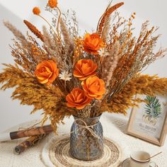 a vase filled with orange flowers on top of a table next to an empty cup