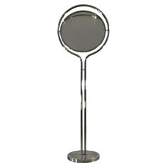 a metal stand with a mirror on it's top and an oval shaped object in the middle