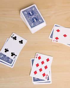 four playing cards on a wooden table with one card in the middle and three out