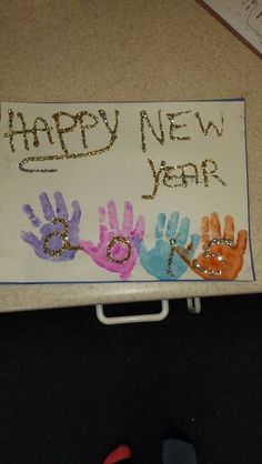 a sign that says happy new year with hand prints on it