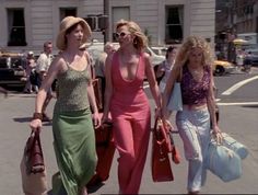 three women walking down the street with bags in their hands and one woman carrying shopping bags