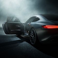 the rear end of a sports car with its door open in a foggy area