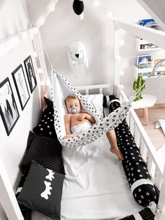 a small child laying in a bed with a hammock hanging from the ceiling