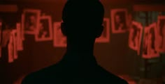 the silhouette of a man standing in front of a wall with red letters on it