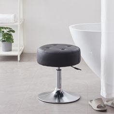 a white bath tub sitting next to a black and chrome foot stool in a bathroom