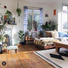 a living room filled with lots of plants next to a fire place in front of a window