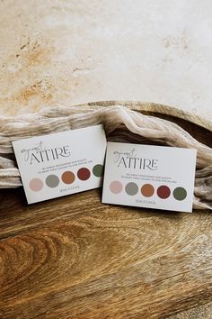 two business cards sitting on top of a wooden table next to a cloth covered bowl