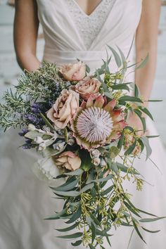 a bride holding a bouquet of flowers and greenery