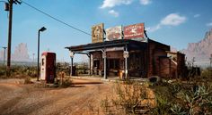 an old western gas station in the desert with mountains in the backgrouds