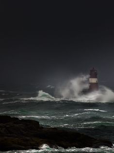 the lighthouse is surrounded by rough waves in the dark ocean, with an approaching storm