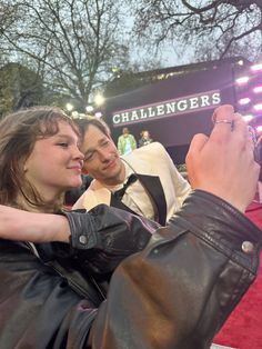 two people taking pictures with their cell phones on the red carpet at an awards event