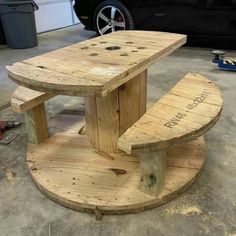 a wooden bench sitting on top of a pallet in front of a black car