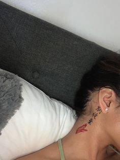 a woman laying in bed with a tattoo on her neck