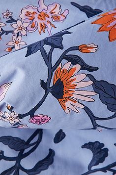 the fabric has flowers on it and is blue with orange, pink and white colors