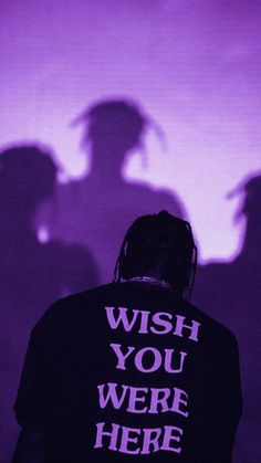 the shadow of a man with his back turned against a purple background that says wish you were here