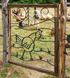 a metal gate with chickens on it in the grass