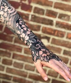 a woman's arm with flowers on it and a brick wall in the background