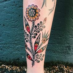 a woman's leg with tattoos and flowers on it