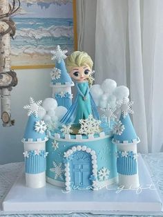 a frozen princess castle cake with snowflakes on it and a doll in the middle