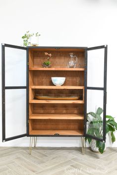 an open cabinet with plants and plates in it