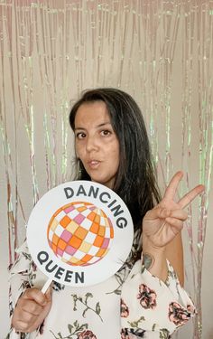 a woman holding up a sign with the words dancing queen written on it in front of her face