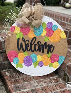 a welcome sign on the side of a brick wall with a bow hanging from it