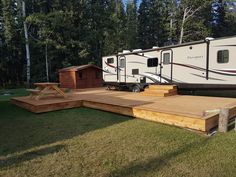 an rv is parked on the grass next to a picnic table and steps leading up to it