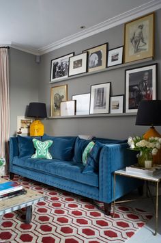 a living room with blue couches and pictures on the wall above it's windows