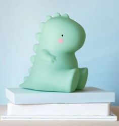 a green toy sitting on top of a stack of books