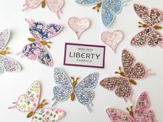 there are many butterflies on the table with a sign that says make with liberty fabrics