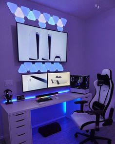 a computer desk with two monitors on top of it in front of a purple wall